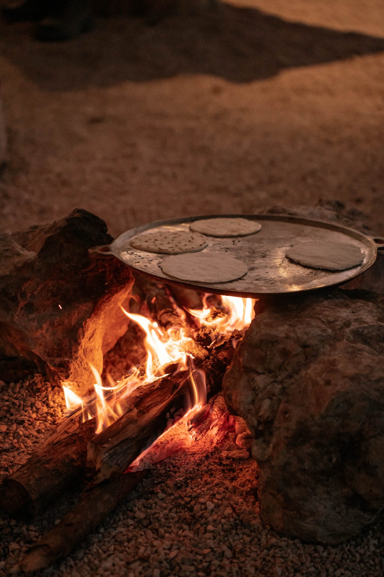 Comal sobre leña encendida con tortillas cociéndose de noche