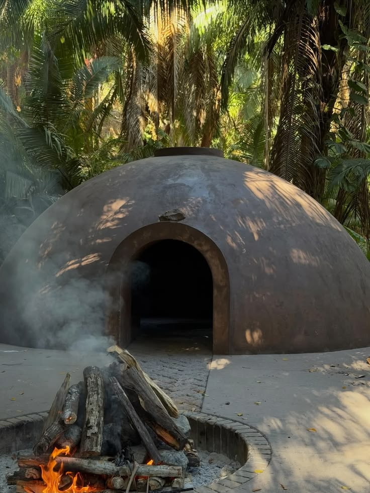 Temazcal de barro con fuego encendido entre palmeras