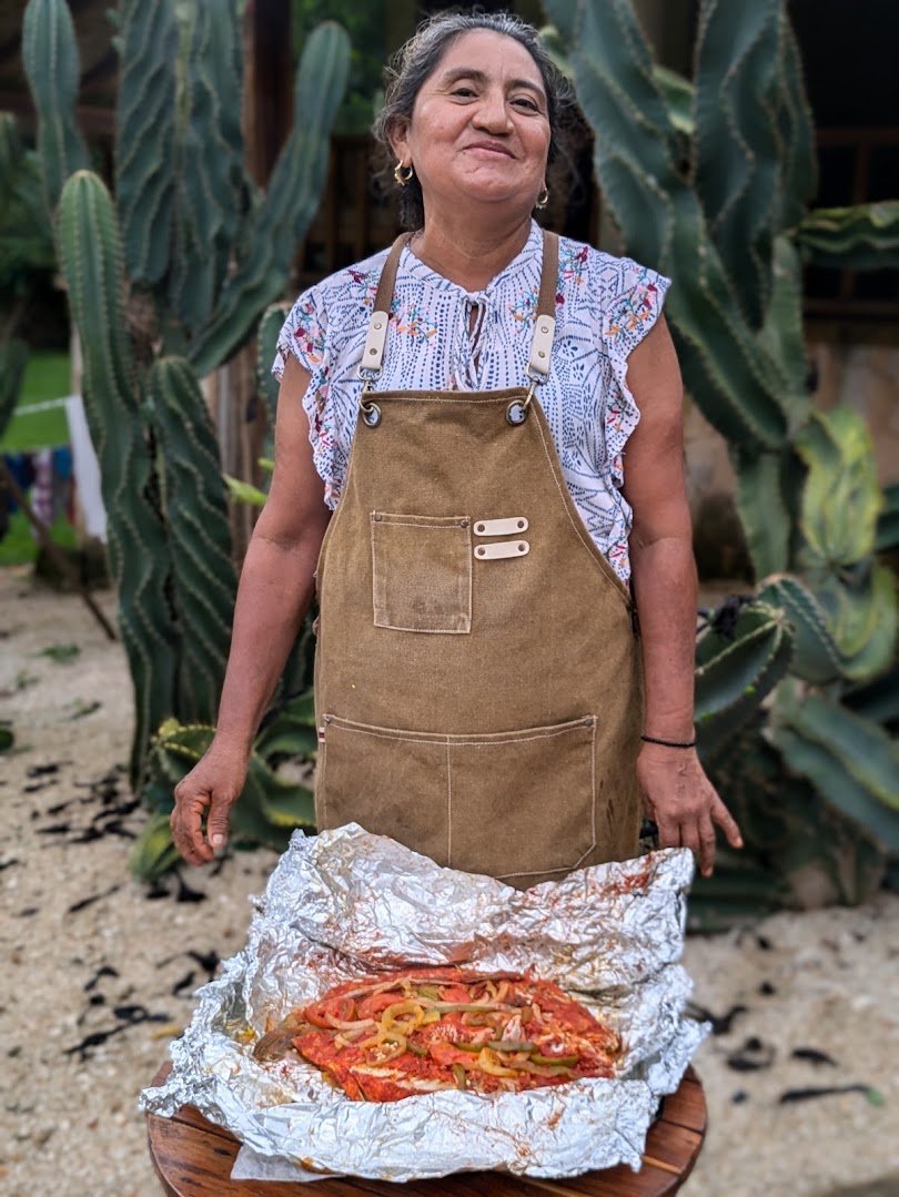 Cocinera presentando pescado a la veracruzana recién salido del píib