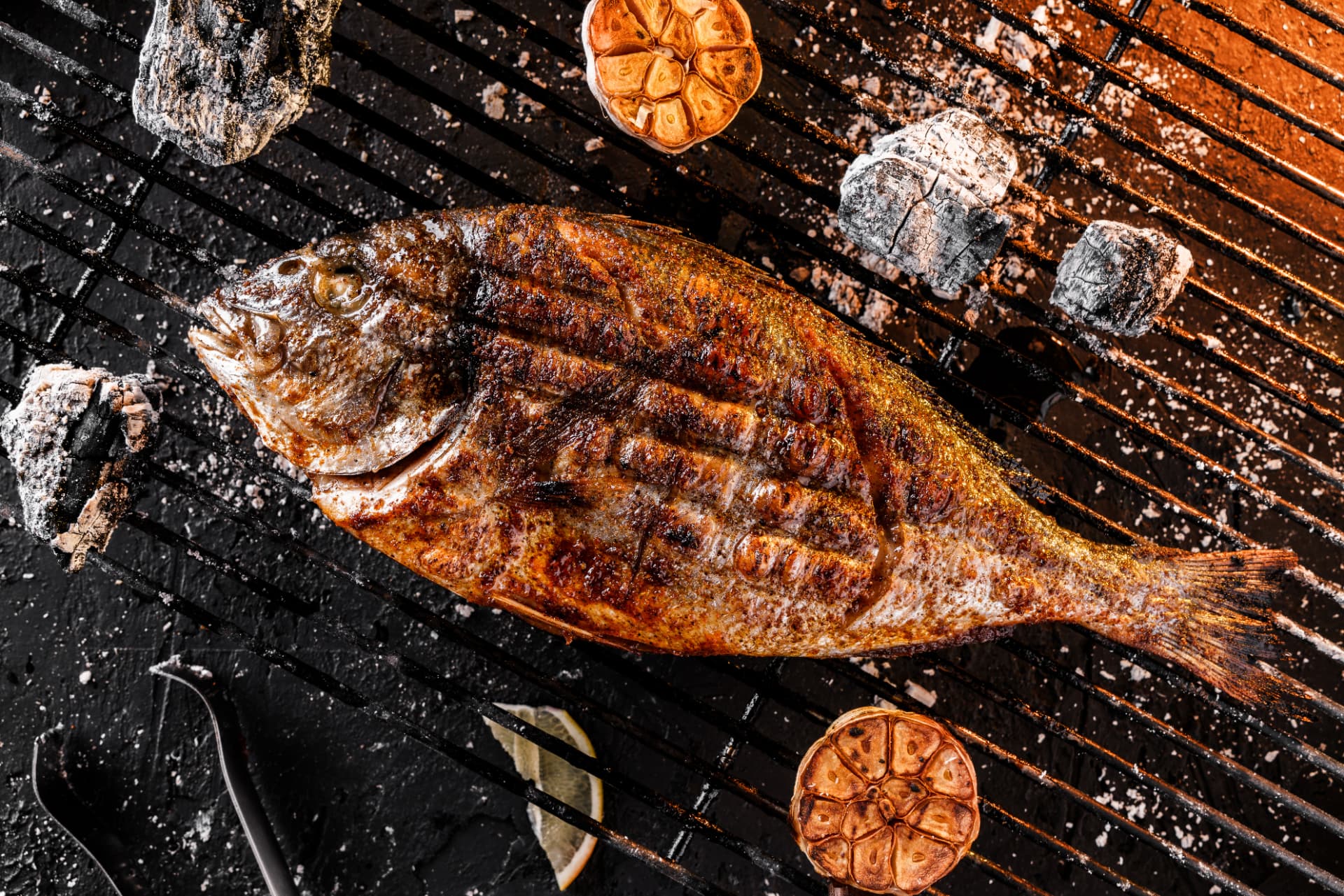 Pescado entero asado a la parrilla con ajo y limón sobre brasas