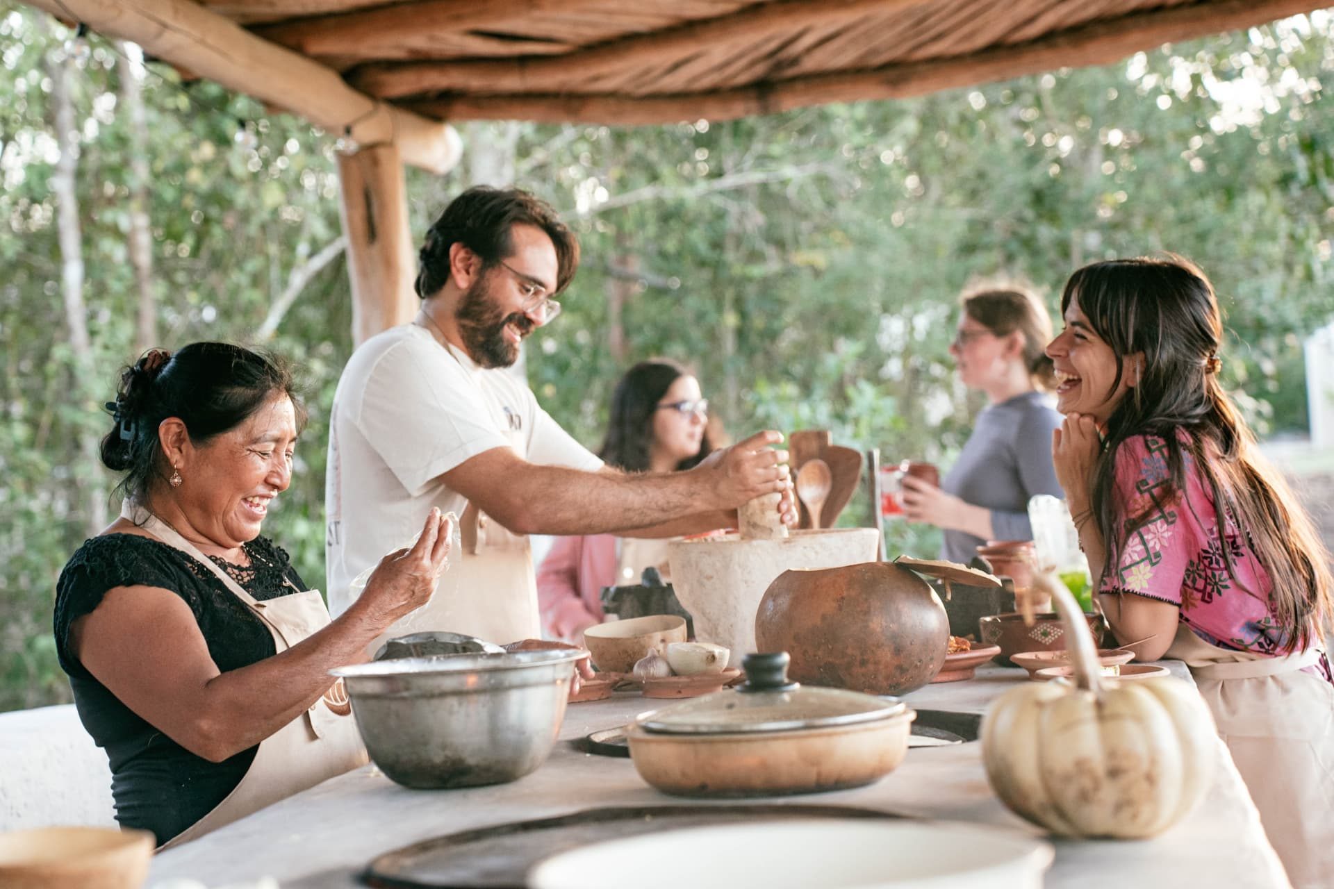 Cocineras y huéspedes moliendo en el metate entre risas