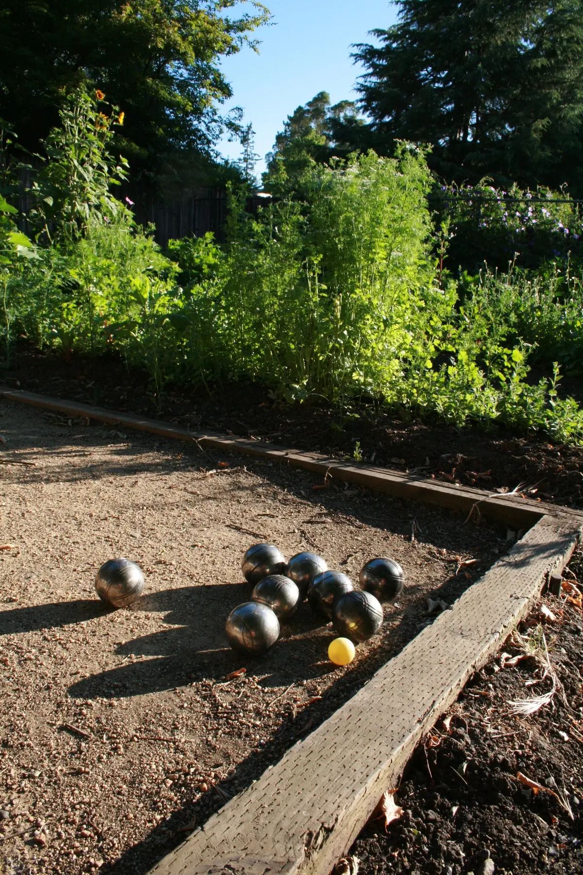 Bolas de petanca sobre la cancha de grava junto al huerto